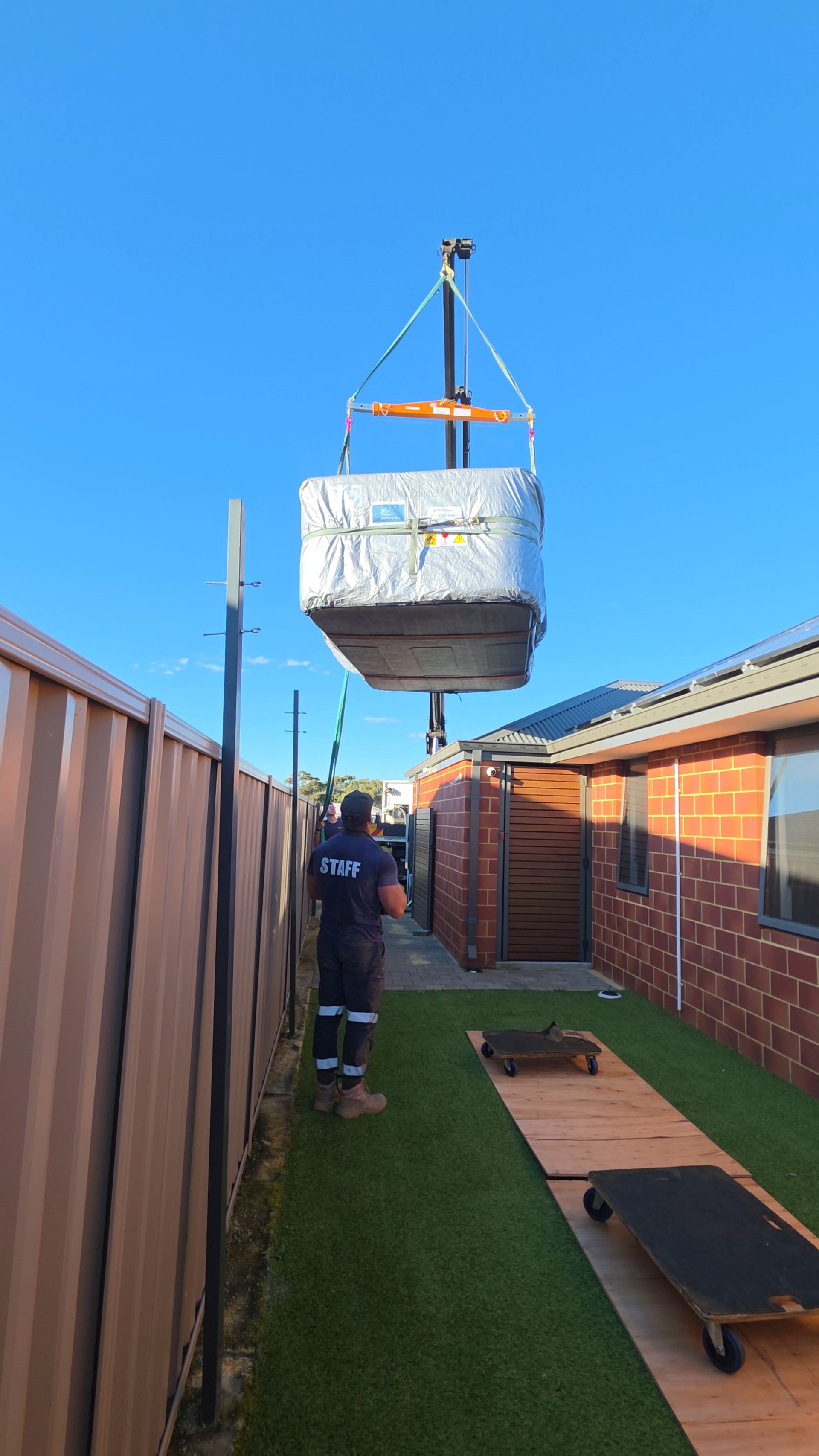 Spa being lowered into a tight Perth backyard beside a fence