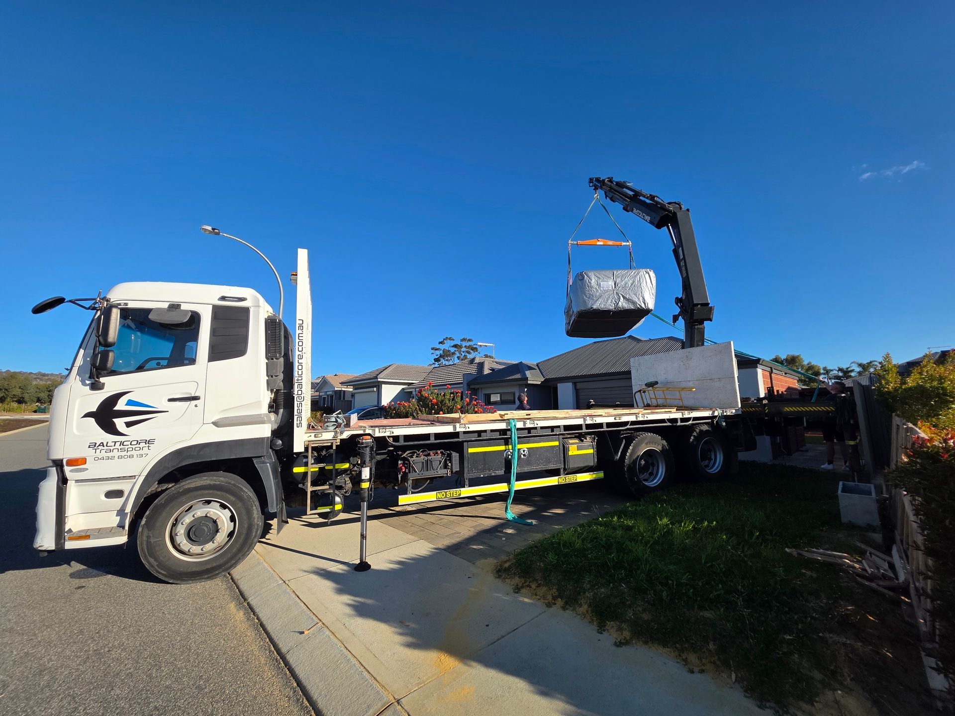 Balticore Hiab crane truck lifting a wrapped spa on a Perth residential street