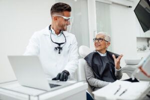A Dental Professional in a White Coat Talks to a Patient in a Dental Chair — Killara Dental in East Killara, NSW