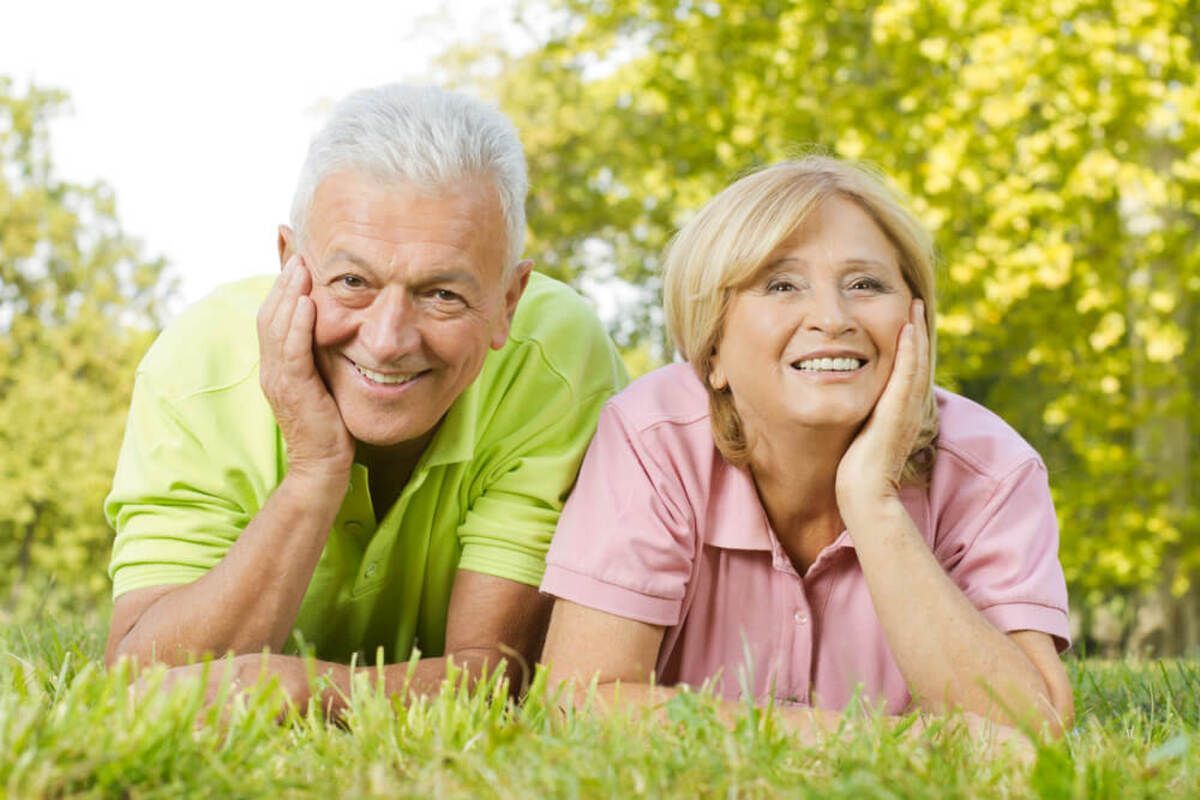 Two People Wearing Casual Shirts Lie in Green Grass — Killara Dental in East Killara, NSW