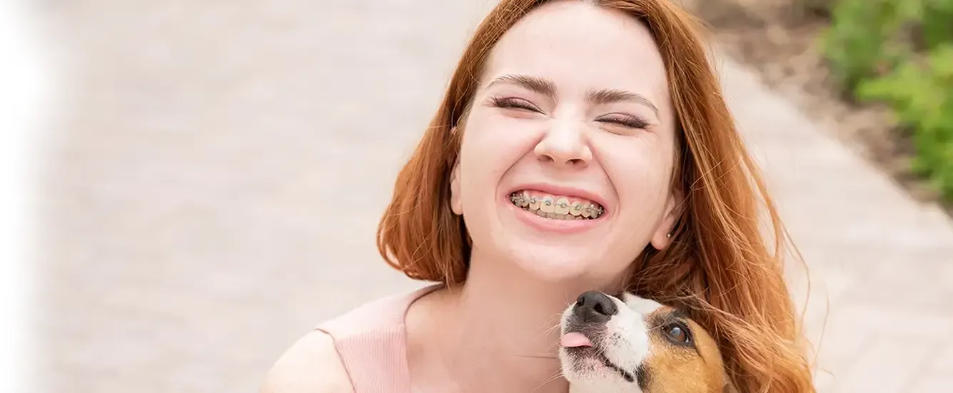 A Smiling Girl with Braces Holding a Puppy — Killara Dental in East Killara, NSW