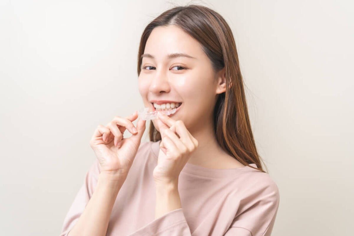 A Person Smiling and Holding a Transparent Dental Aligner — Killara Dental in East Killara, NSW