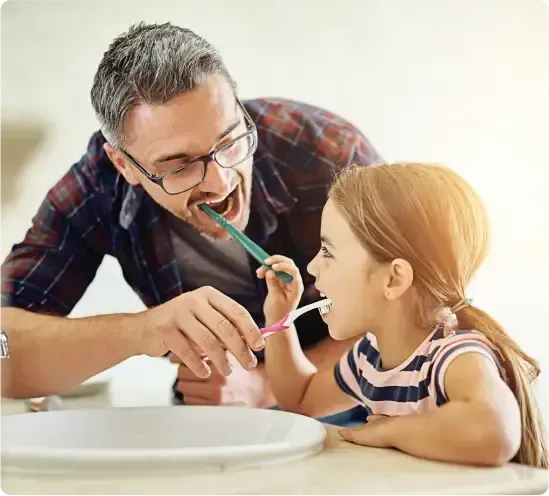 Man and a Child Are Smiling While Brushing Their Teeth — Killara Dental in East Killara, NSW