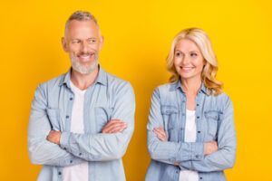 A Smiling Couple Standing Side-by-side With Arms Crossed — Killara Dental in East Killara, NSW