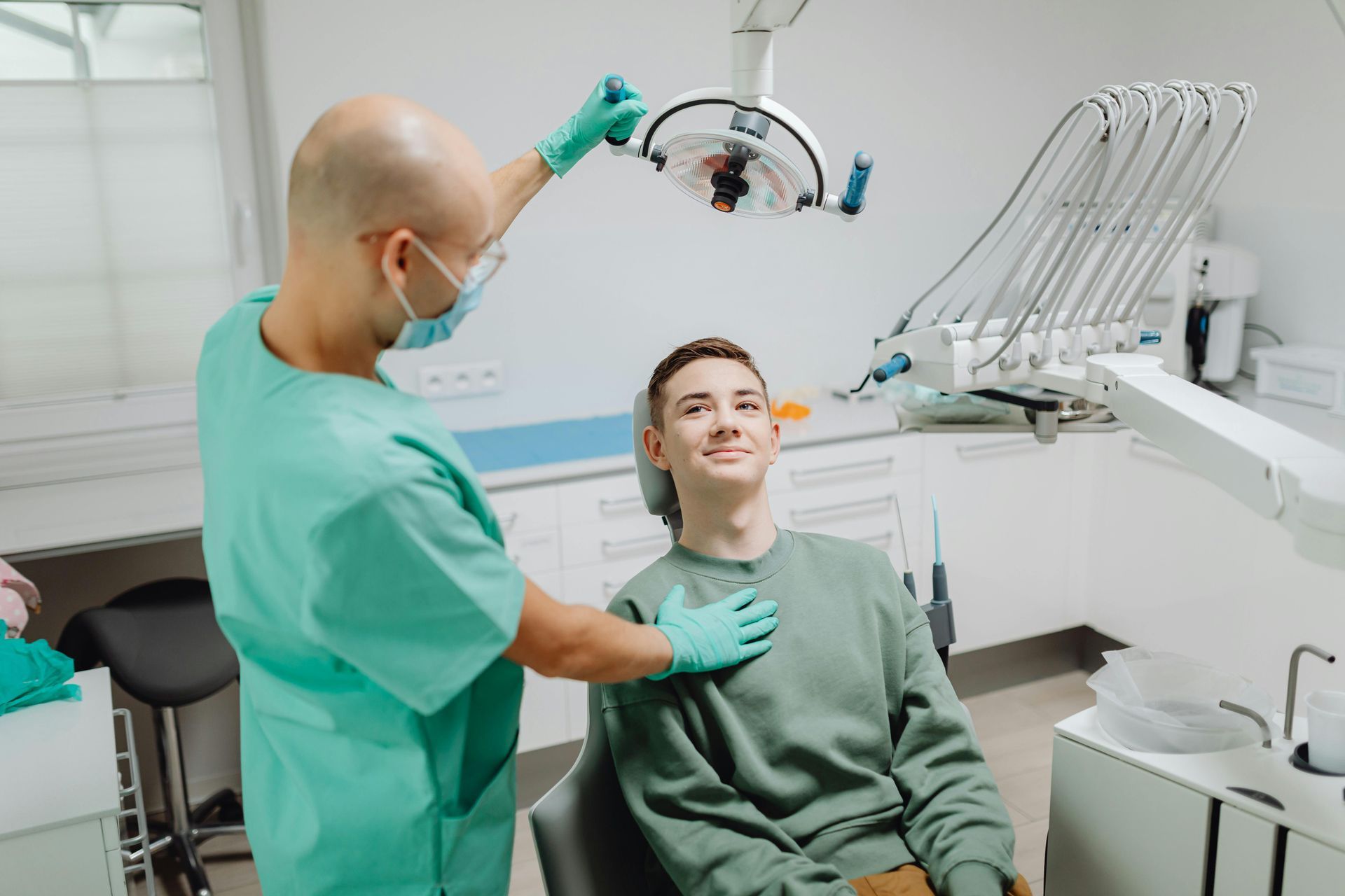 Dental patient smiling in a chair while a dentist points to her teeth during a checkup — Killara Dental in East Killara, NSW