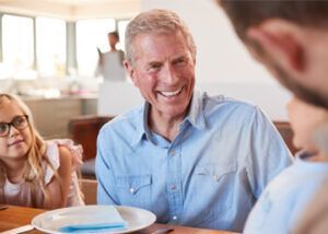 A Smiling Person in a Blue Shirt Sits at a Dining Table With a Child — Killara Dental in East Killara, NSW