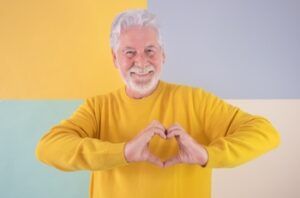 A Smiling Person Wearing a Yellow Sweater Makes a Heart Shape — Killara Dental in East Killara, NSW