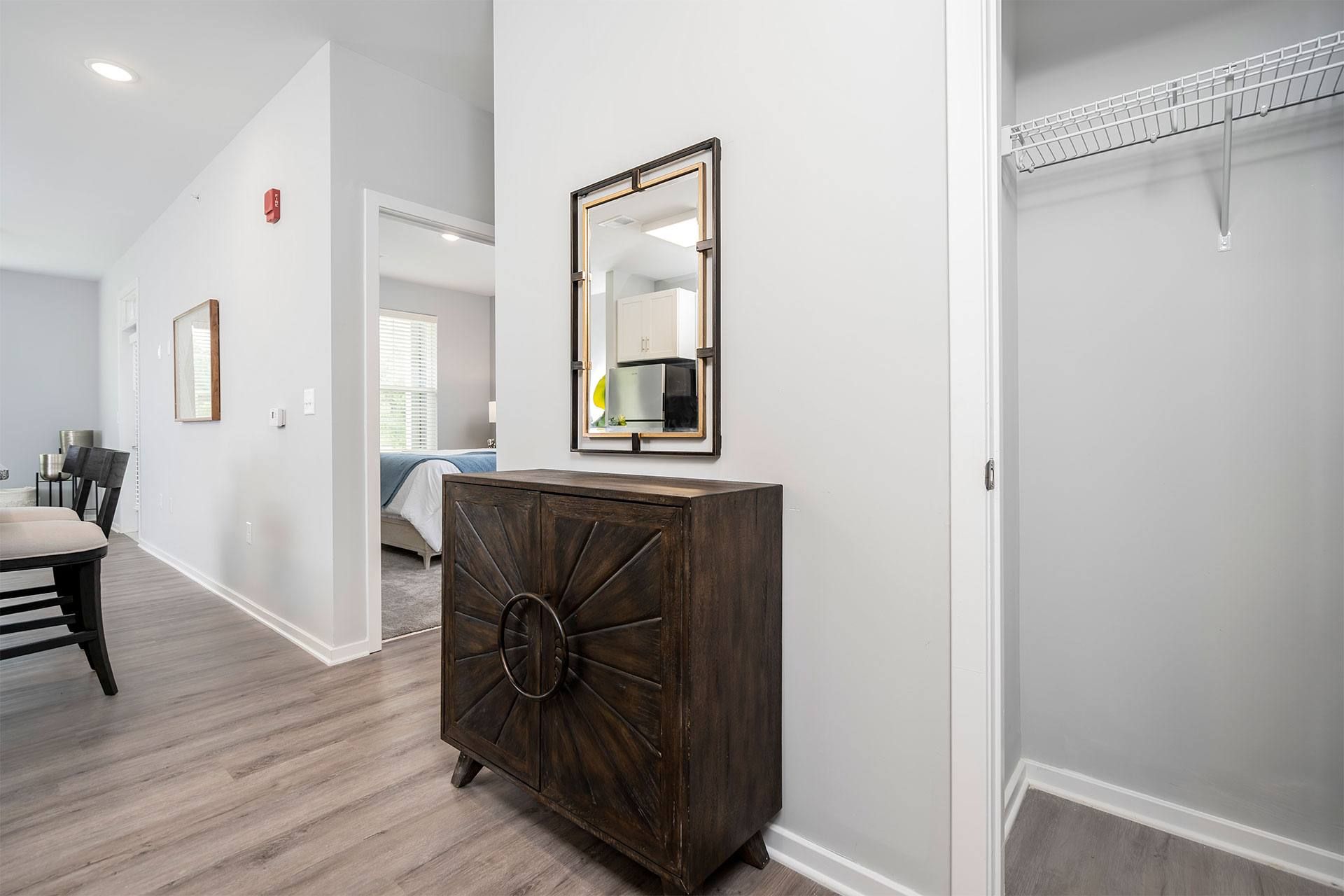 A brown wooden chest of drawers with a mirror on top is in a room with white walls.