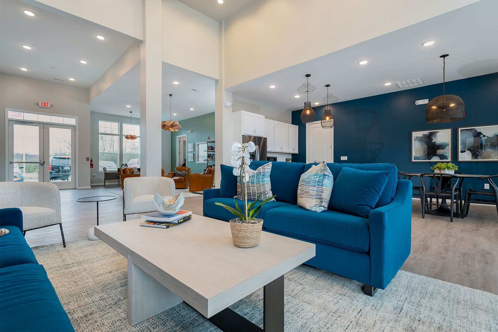 A blue couch sits in a spacious living room with a white coffee table in front of it.