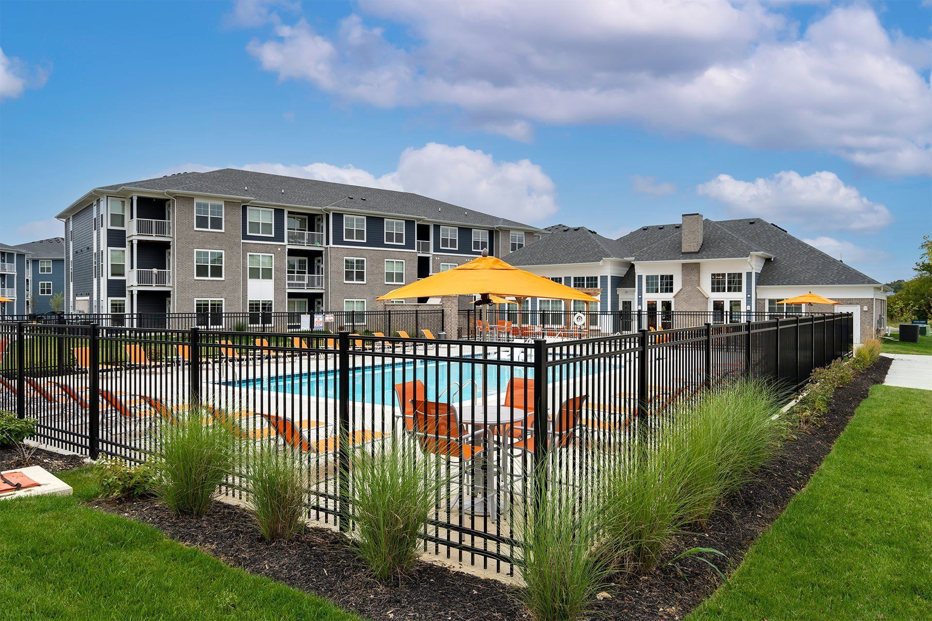 A pool surrounded by a black fence with a yellow umbrella.