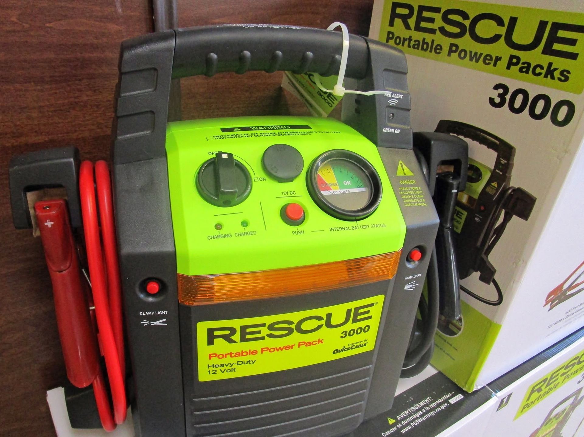Green and black RESCUE 3000 portable power pack with red jumper cables on display