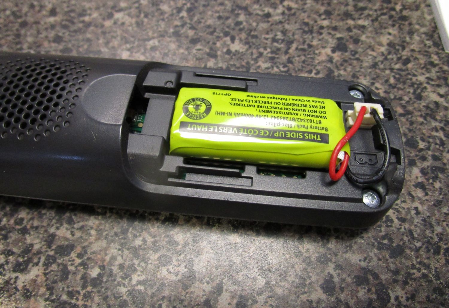 Open battery compartment of a black device with a green rechargeable battery inside