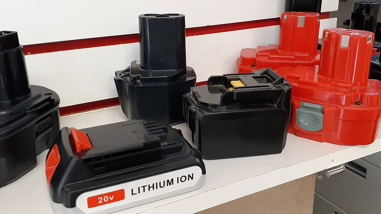 Battery chargers and lithium-ion tool batteries on a store shelf, mostly black and red