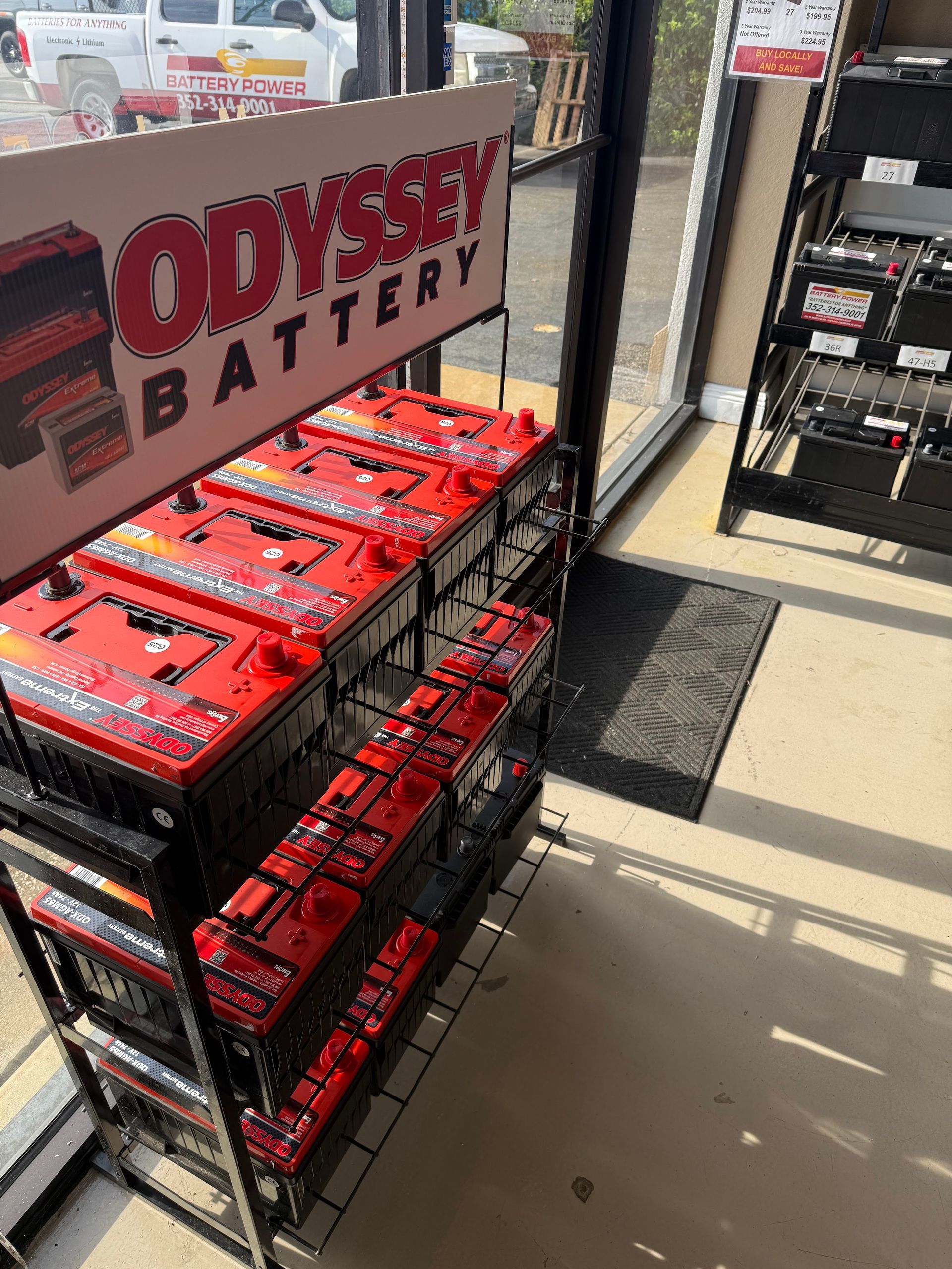 Display of Odyssey car batteries in a store aisle near a front entrance.