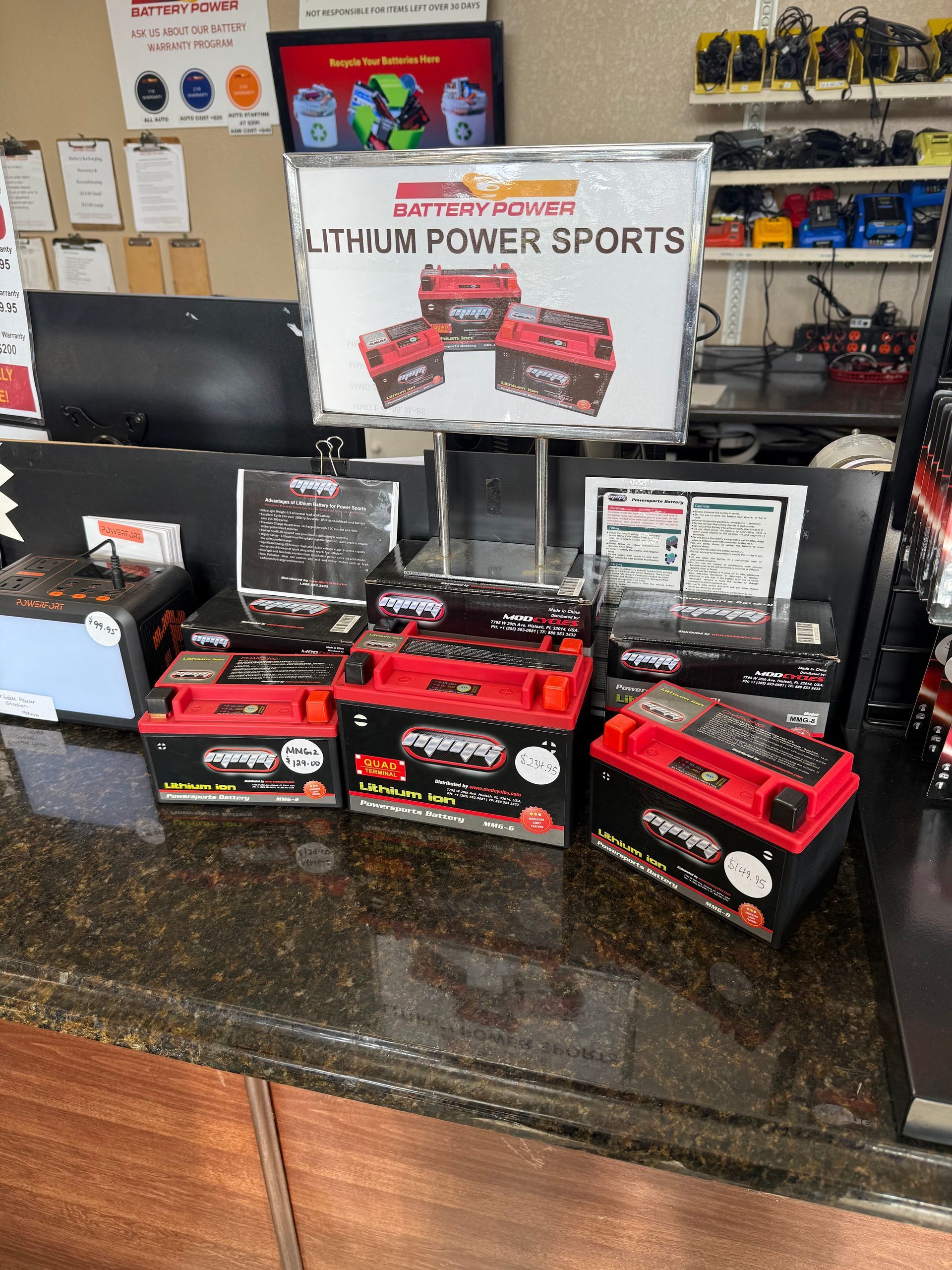 Display table of red and black power sports battery boxes under a Lithium Power Sports sign.