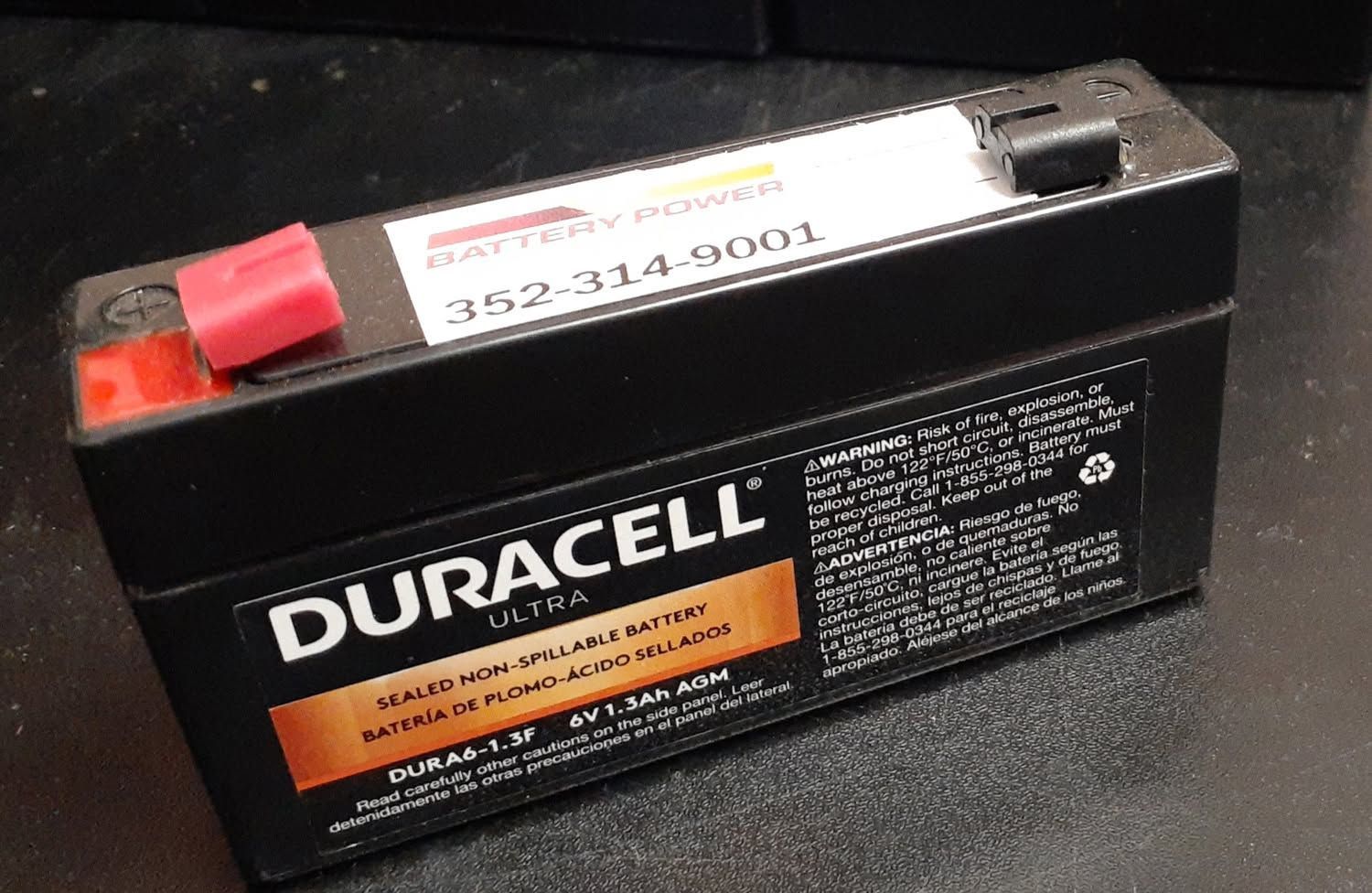 Duracell battery with red positive terminal and white label on a black surface