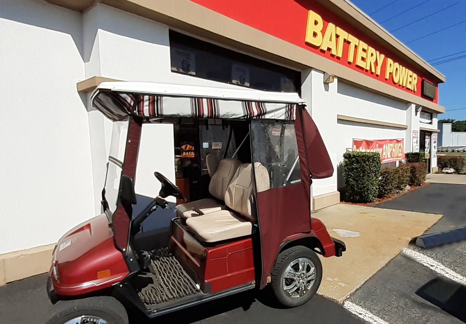 Red golf cart parked outside a Battery Ford store entrance