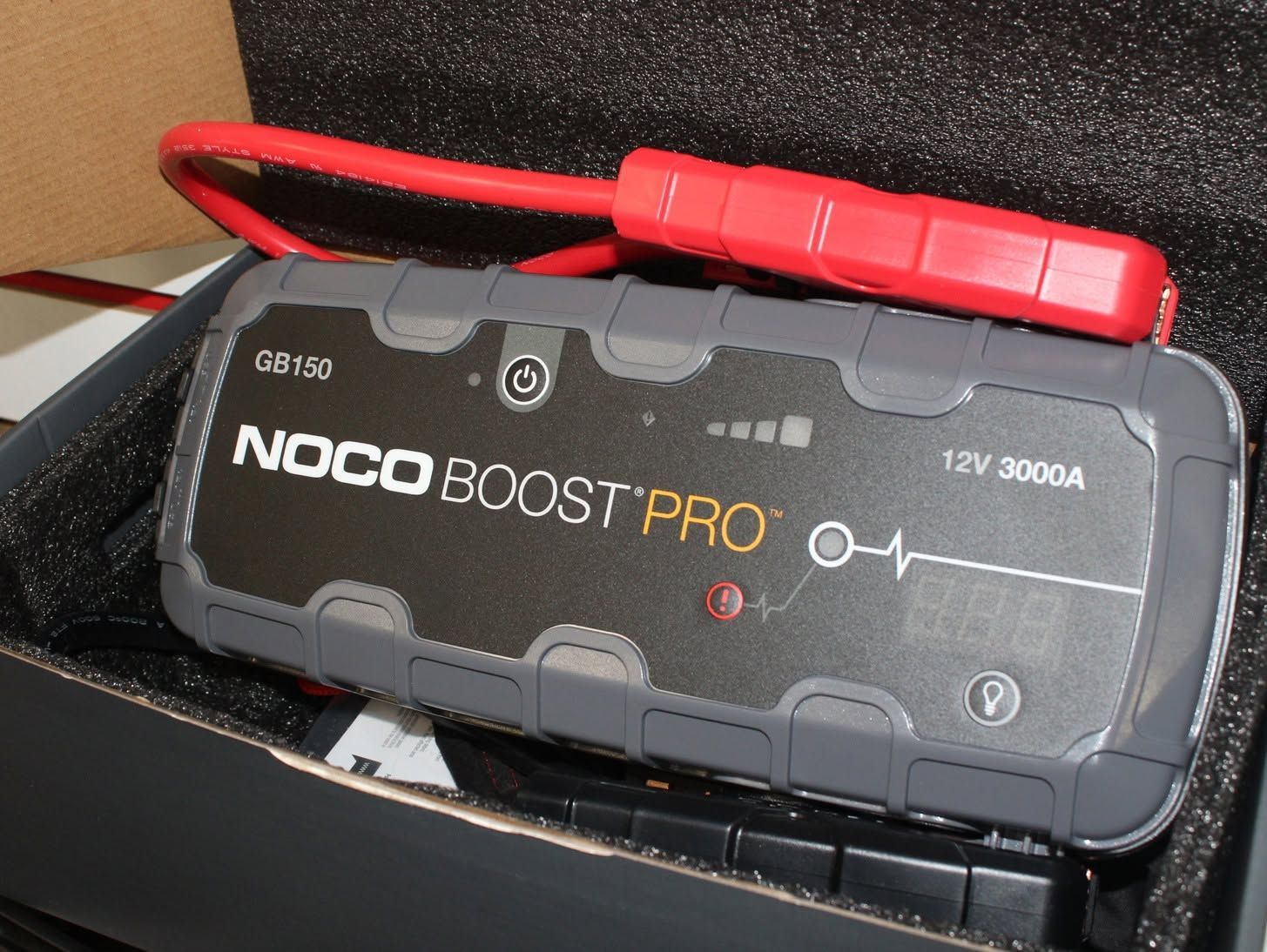 Black NOCO Boost Pro jump starter with red cables in a box