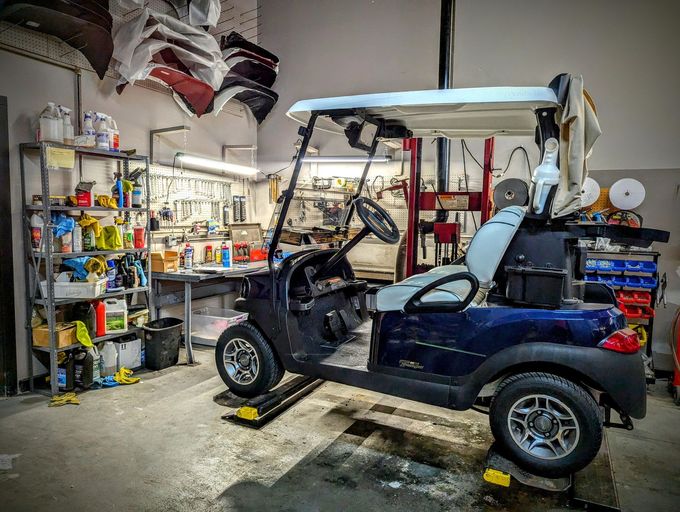 White golf cart with black roof and red seats on a plain white background