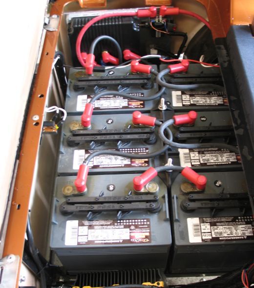Multiple black batteries with red cables inside a battery compartment