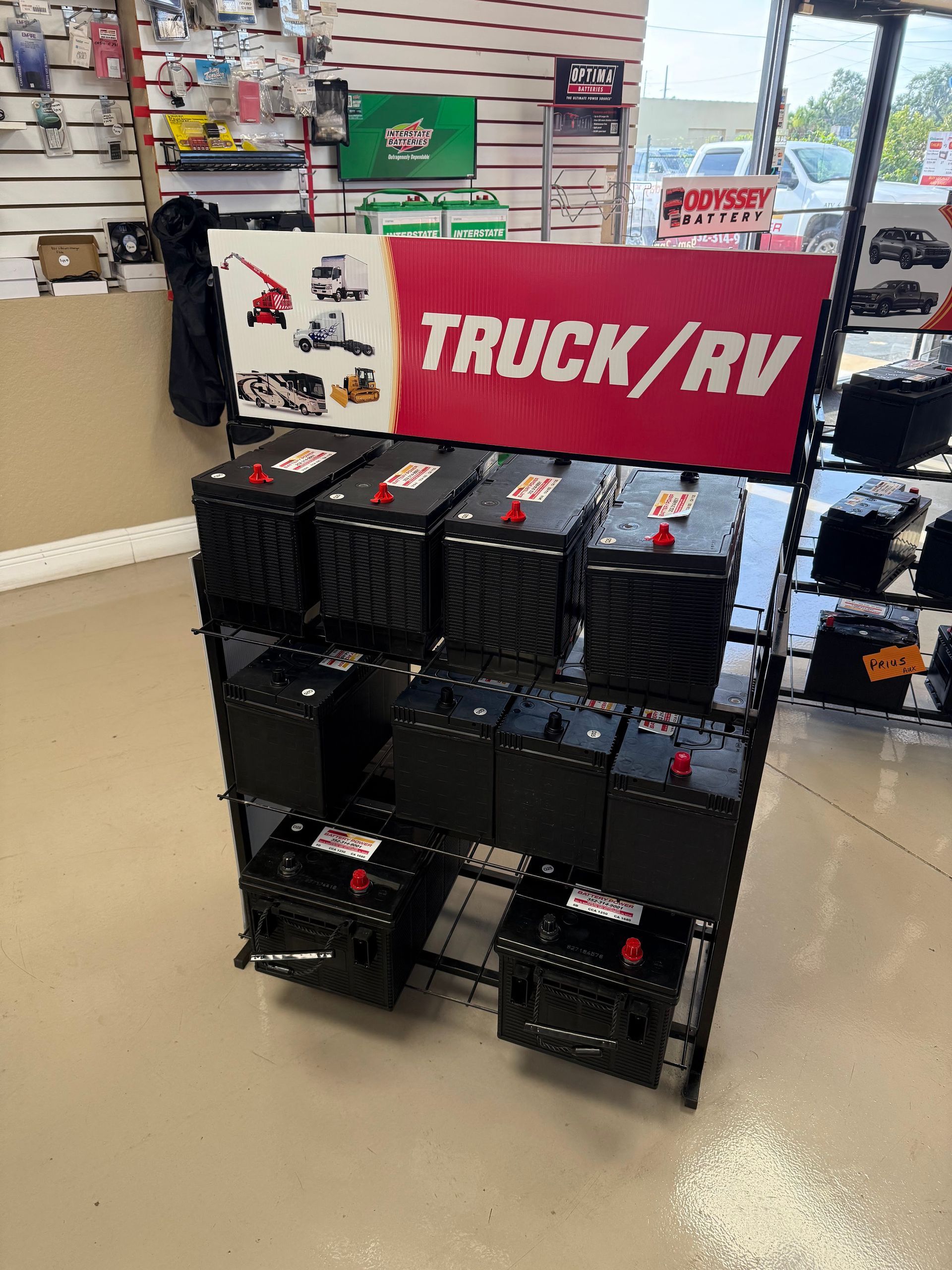 Black truck/RV batteries displayed on a store shelf beneath a red TRUCK/RV sign.