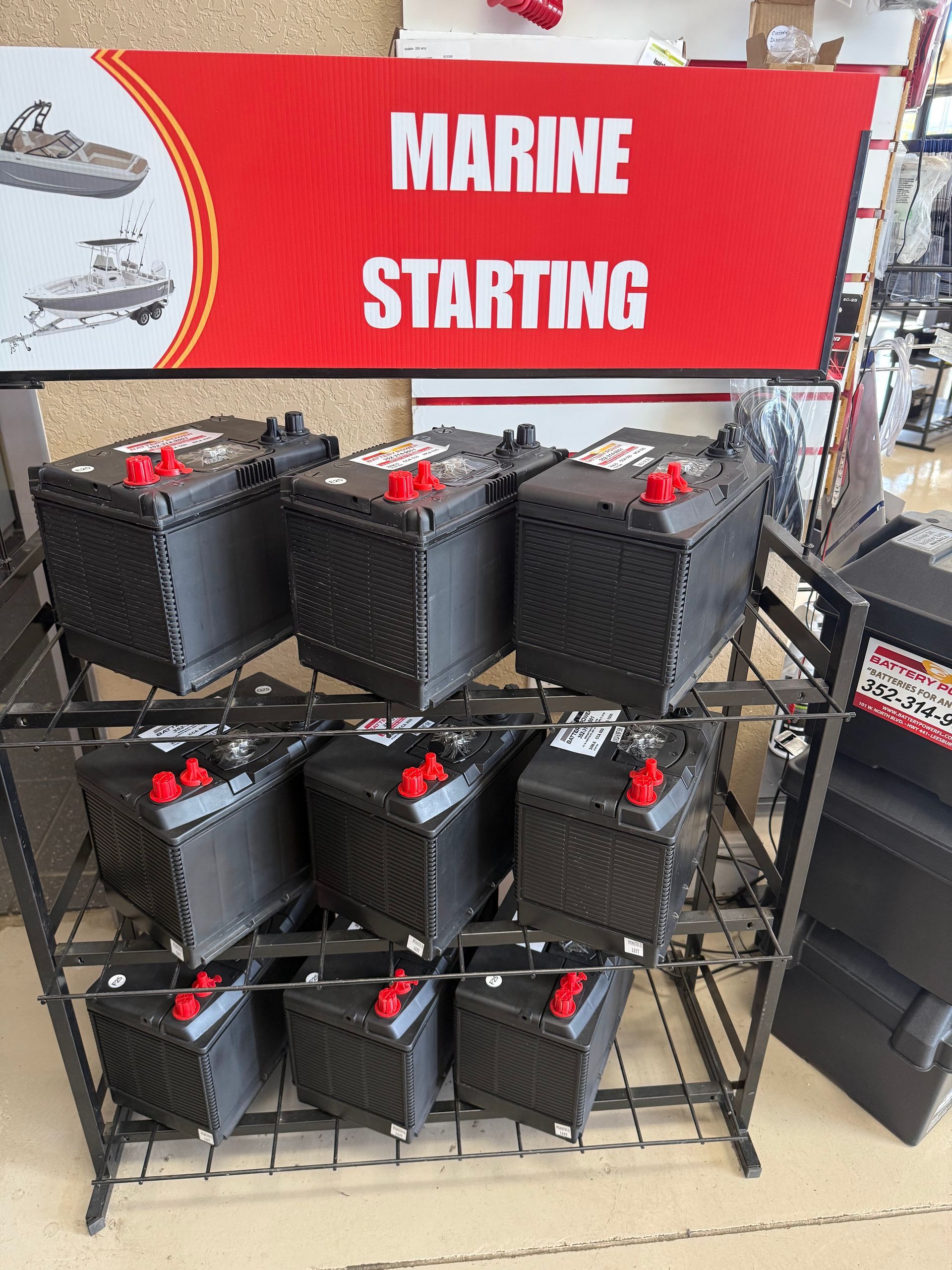 Display of black marine starting batteries beneath a red “MARINE STARTING” sign