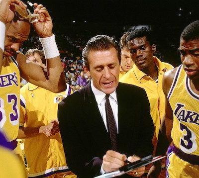 Lakers coach addressing players during a timeout, surrounded by yellow uniforms on the court.