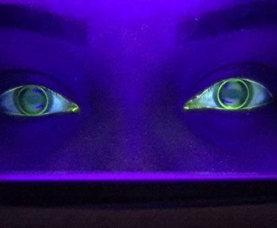 Purple-lit eyes glowing from a dark face, staring forward