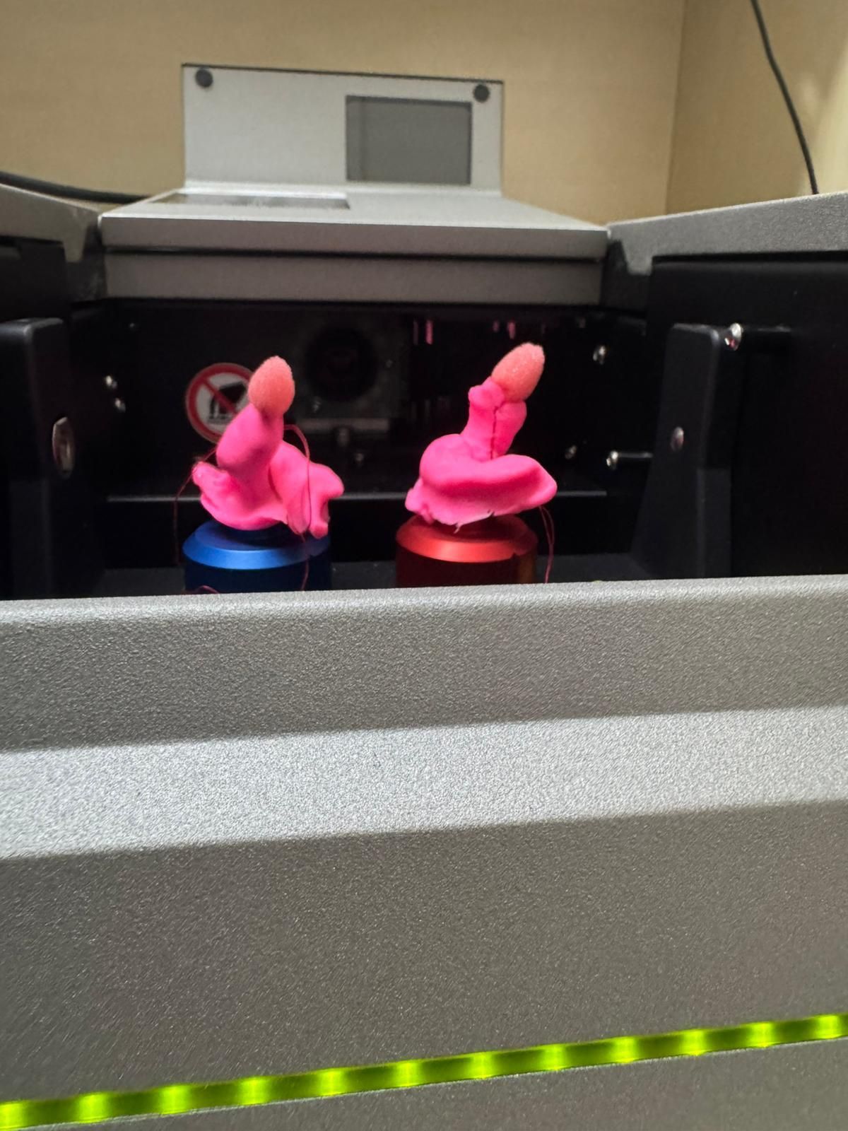 Due peluche rosa su piattaforme luminose all'interno di una macchina o di una teca nera.