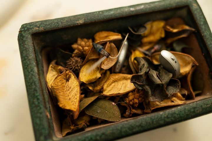 Scatola aperta contenente foglie secche, fiori e un anello d'argento