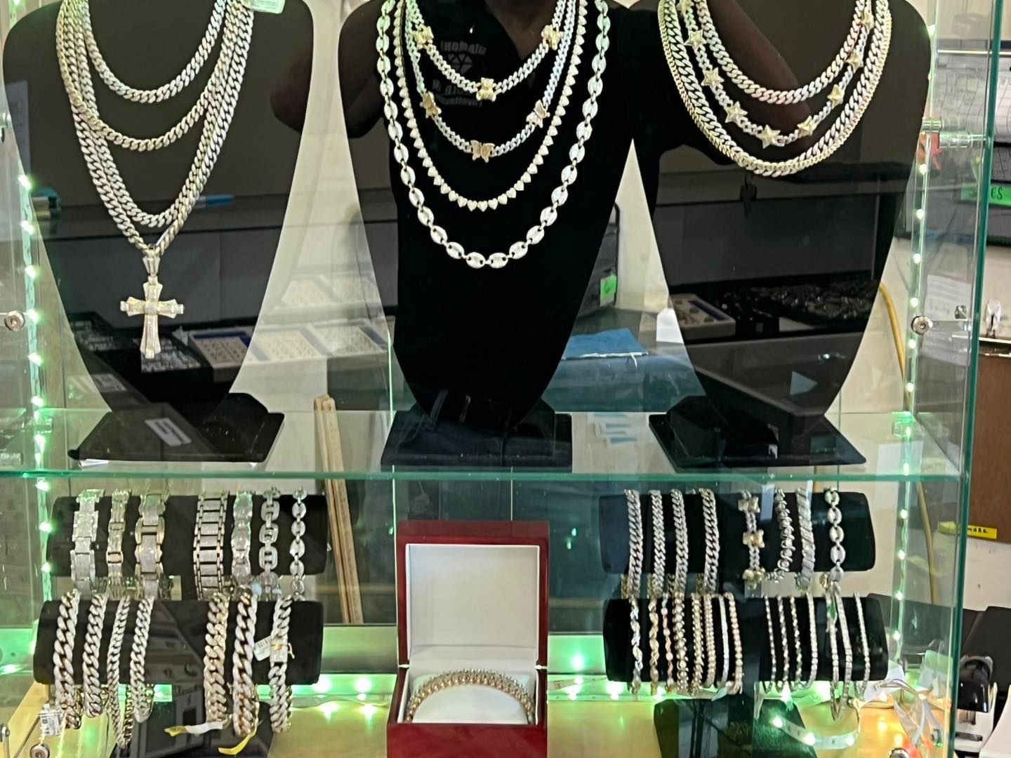 Jewelry display: necklaces and bracelets in a glass case, lit with green lights in Fayetteville, NC.