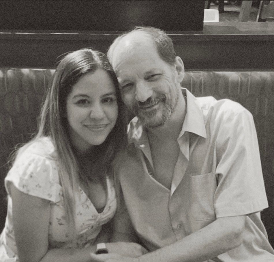 Two people smiling together on a booth bench in a black-and-white photo