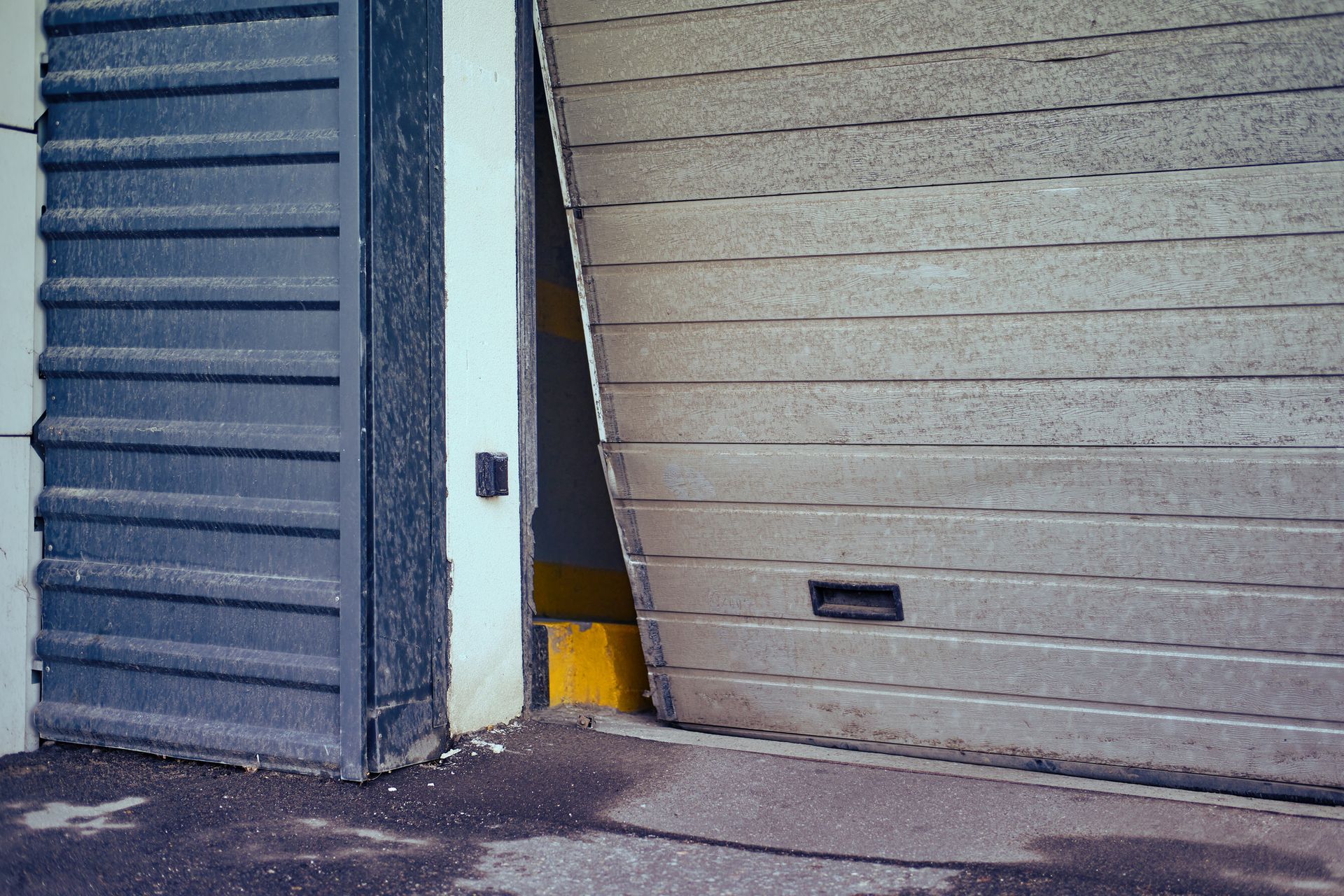 Garage door partially open, showing interior. Grey and yellow accents, outdoor setting.