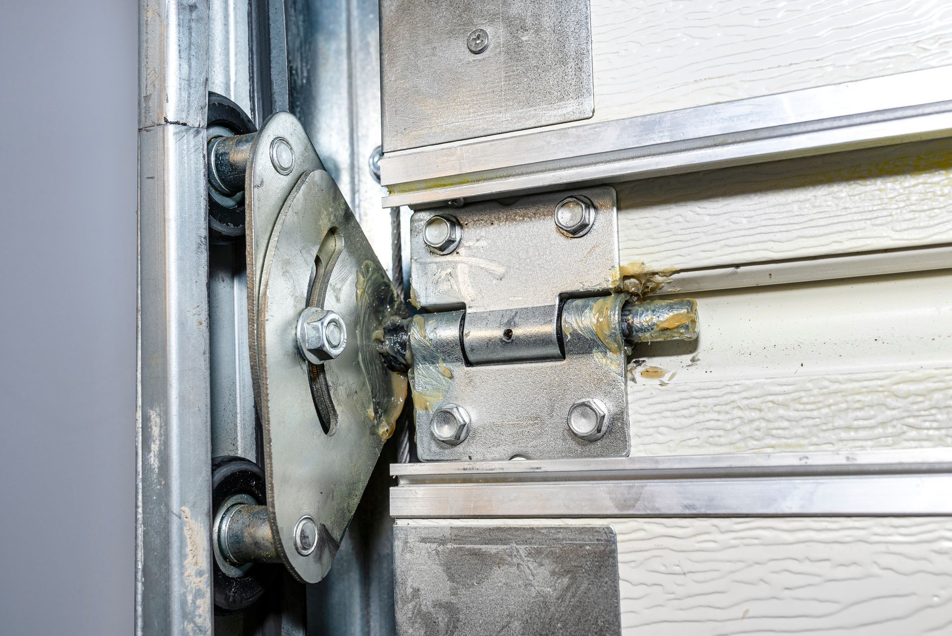 Garage door hinge with a roller, showing wear and grease.