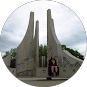 A person sits in front of the tall, angular, concrete pillars of the Memorial to the Victims of Communism in Ottawa.