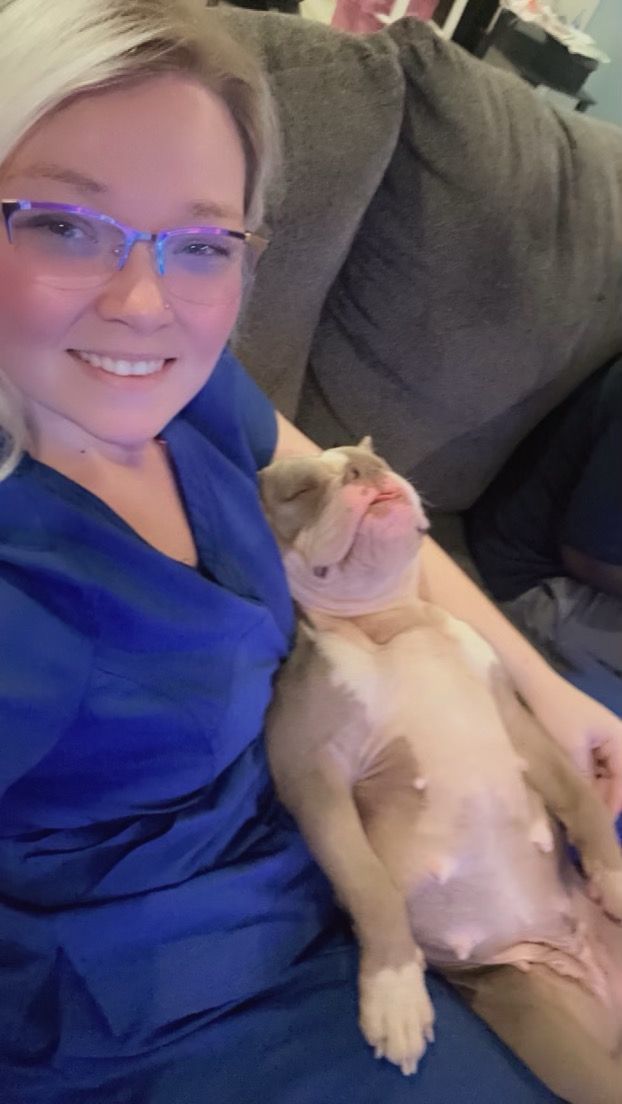 A woman is sitting on a couch with a dog on her lap.