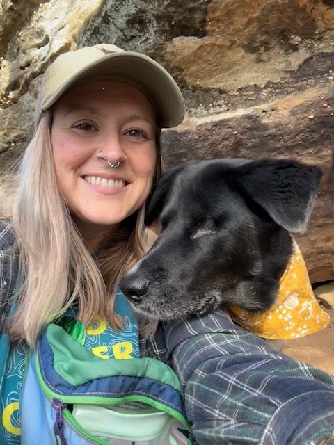 A woman is holding a black dog in her arms.