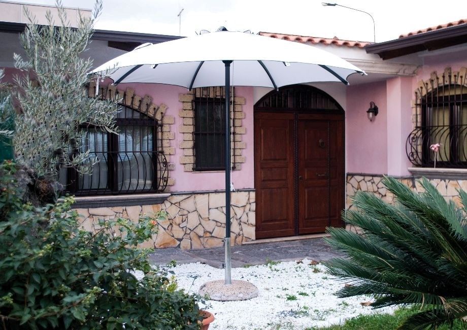 Un ombrello bianco è davanti a una casa rosa