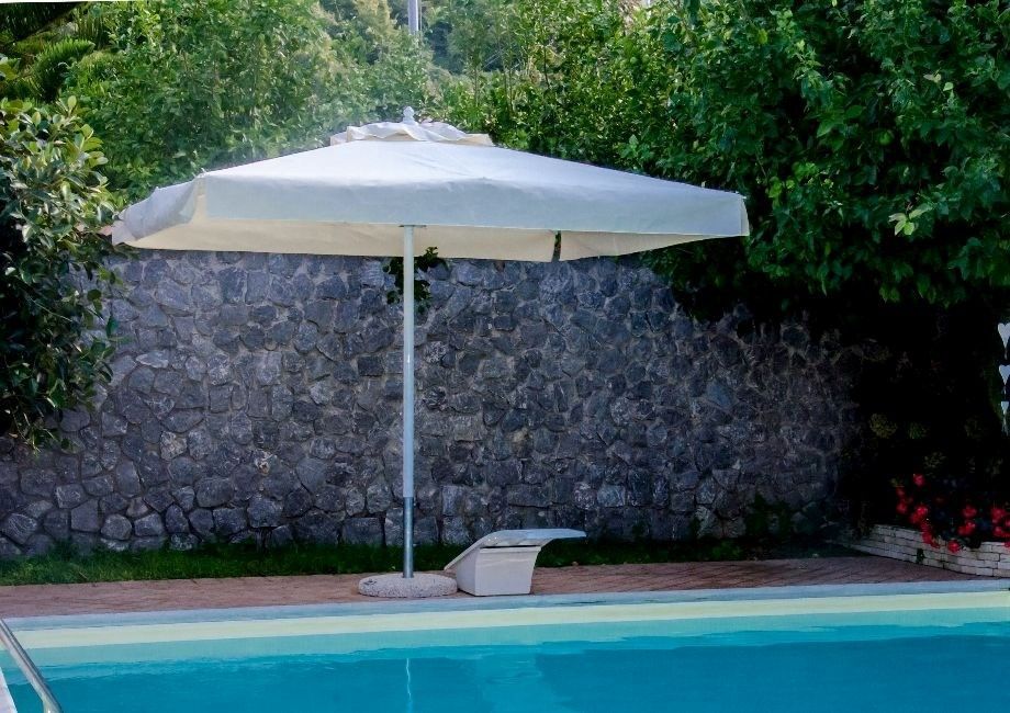 Un ombrellone bianco è appoggiato sul bordo di una piscina.