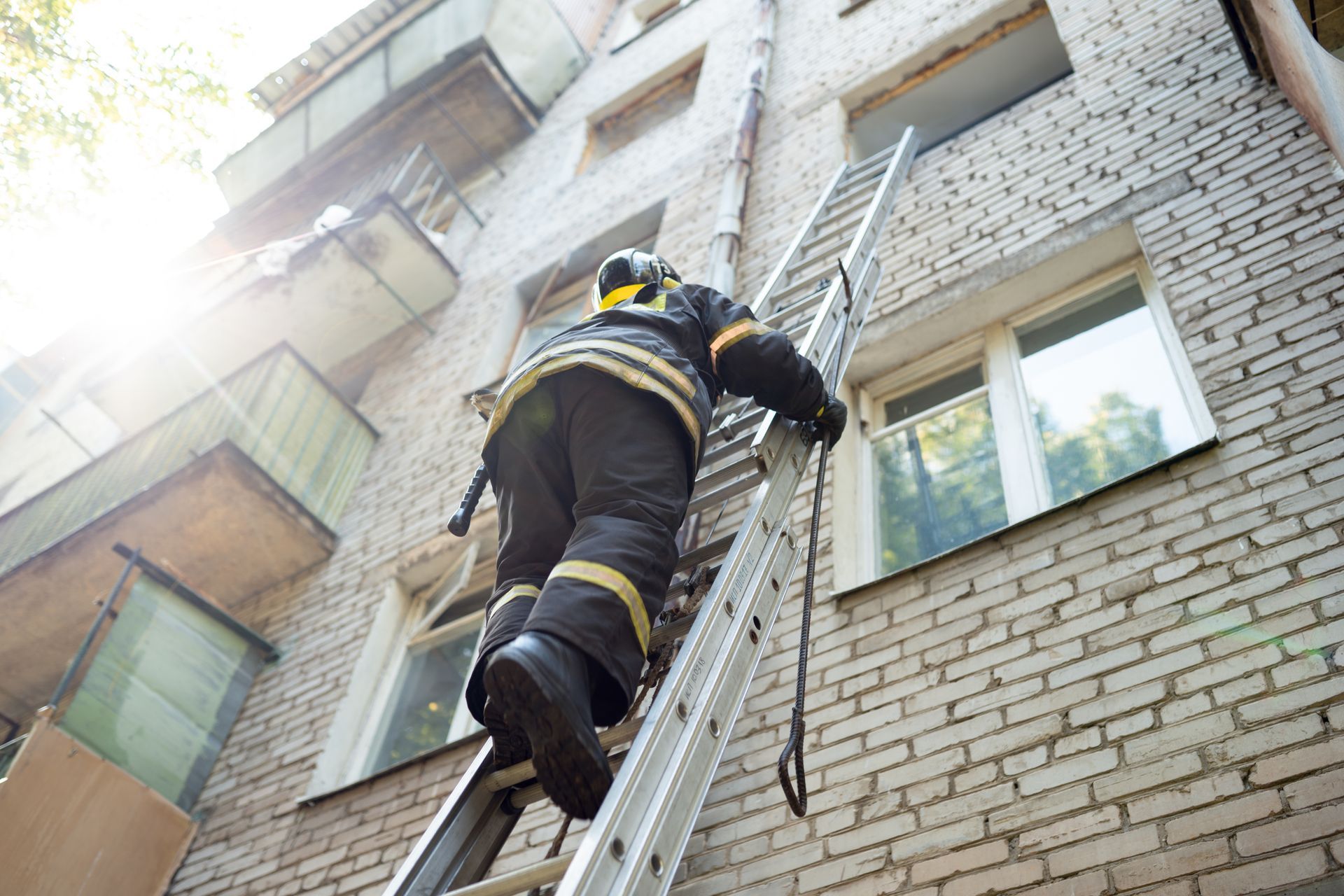 A fireman climbs stairs up in a burning brick building.