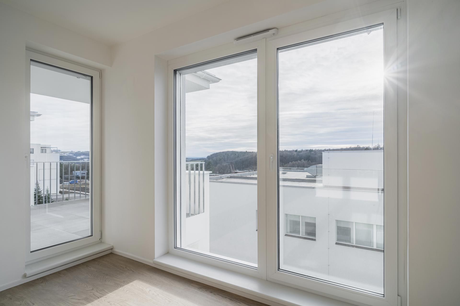 A room with large floor-to-ceiling double-glazed windows that offer a view of modern buildings.