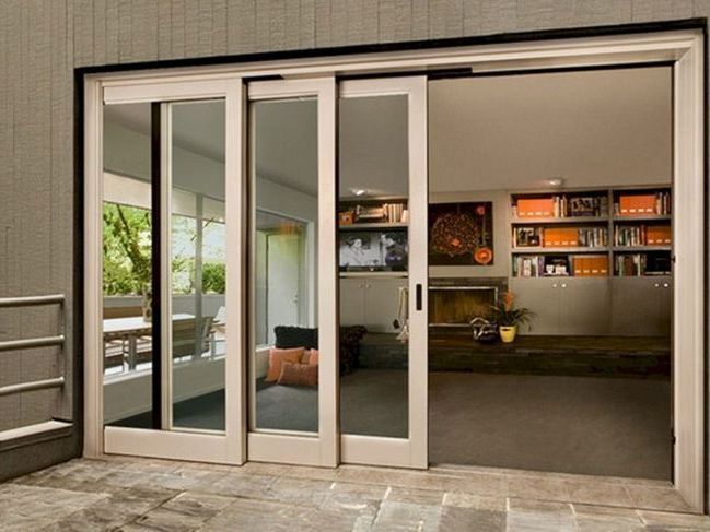 Sliding glass doors open to a light-filled interior. Beige trim, gray flooring, and outdoor patio.