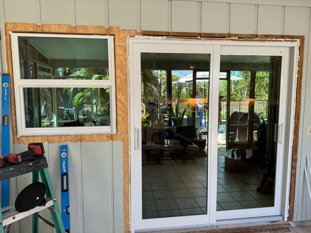 Window and sliding glass door installation; tools, house exterior, natural light.