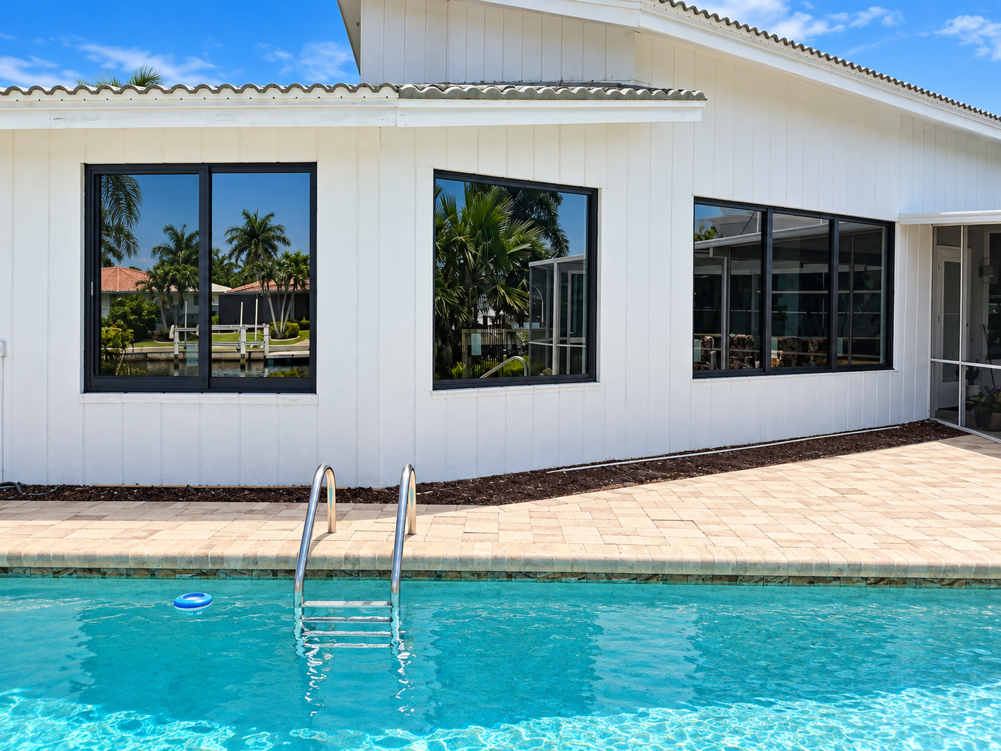 Black-framed impact-resistant windows installed on a Florida home overlooking a swimming pool