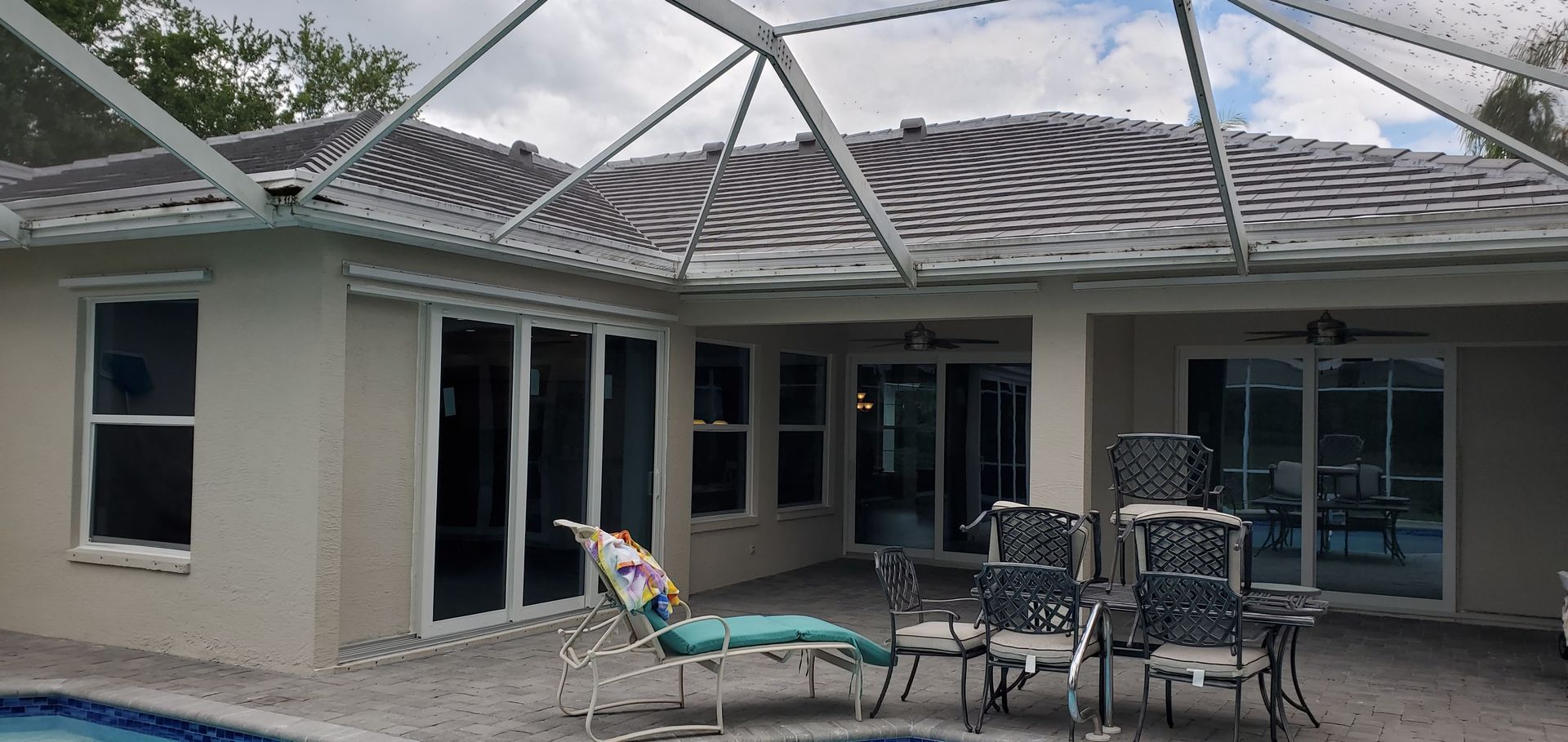 Patio with pool, chairs, and sliding glass doors under a screened enclosure.