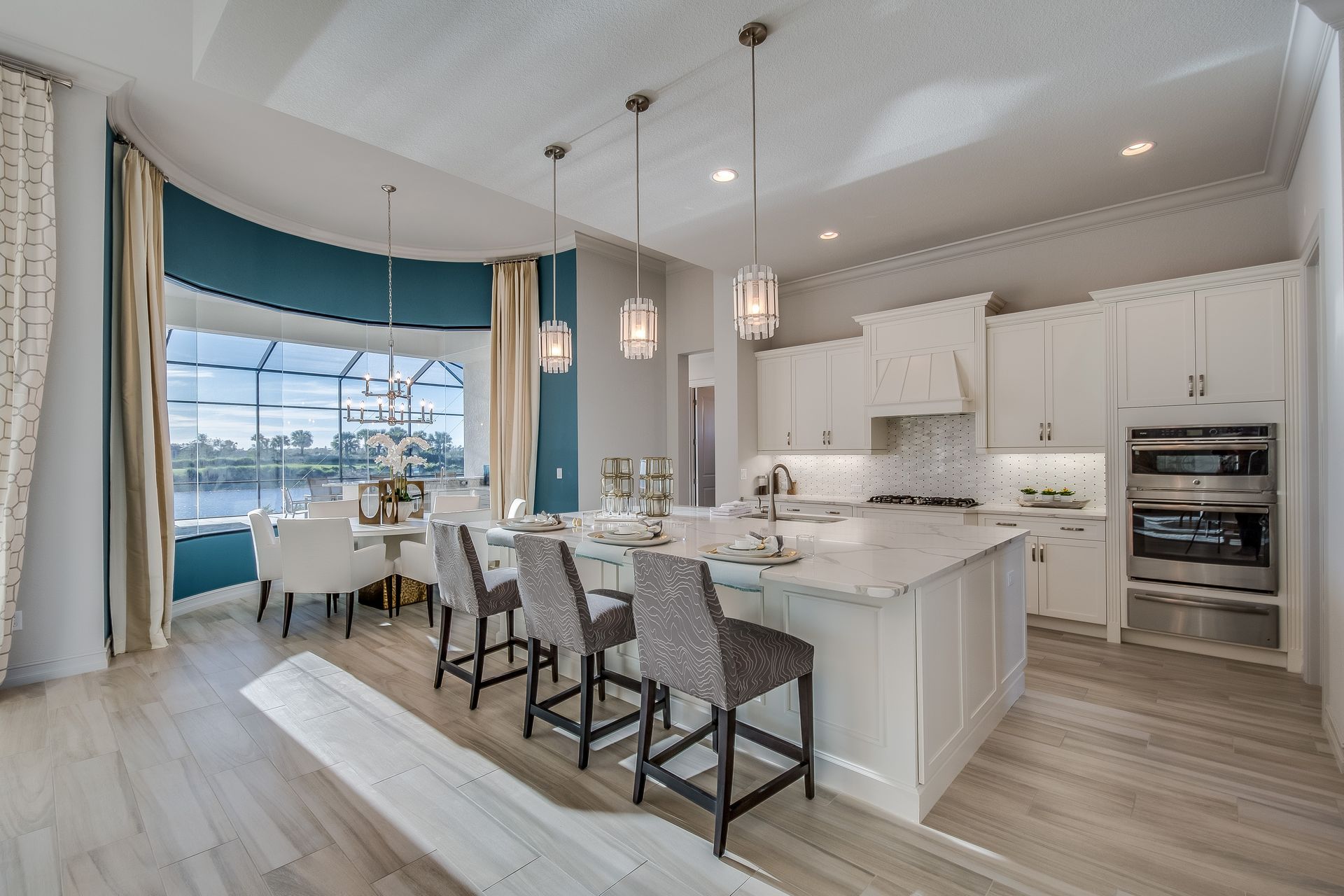 Spacious, light-filled kitchen with an island, dining area, and large window overlooking a lake.