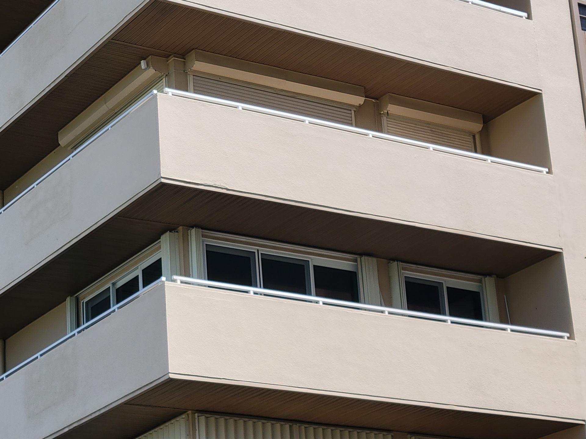 Beige building with balconies, windows, and brown overhangs.