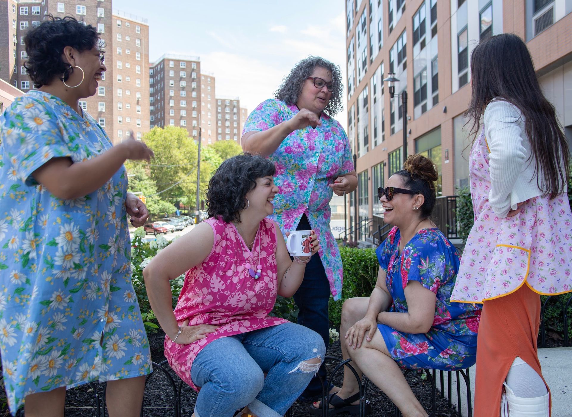 a group of women are sitting on a bench talking to each other .