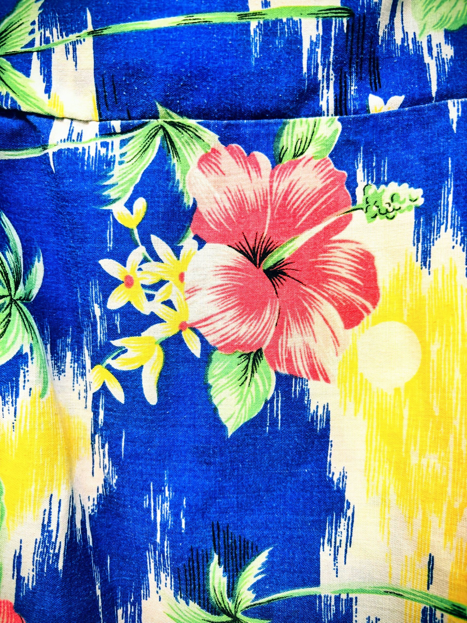 Blue, yellow, and white floral fabric with a pink hibiscus and green leaves