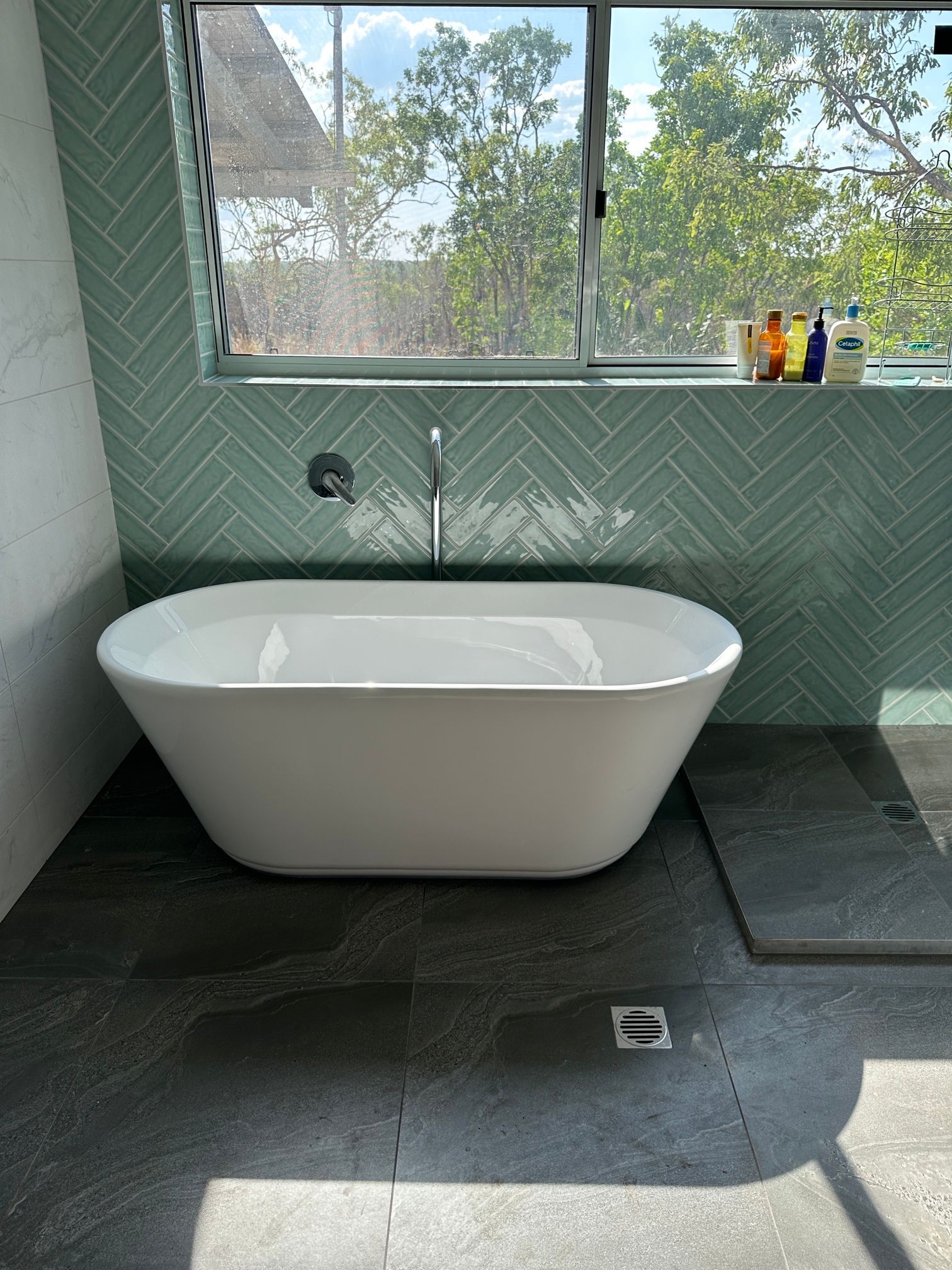 Modern bathtub in a bathroom next to a window.